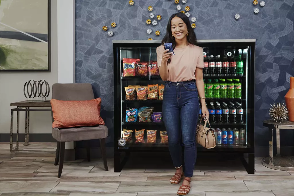 A person holding a snack beside a small market in a lounge.